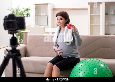 Femme enceinte blogger faisant des exercices physiques Banque D'Images