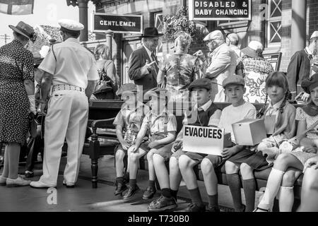 Vue monochrome de Severn Valley Railway, événement de la Seconde Guerre mondiale de 1940, gare de Kidderminster vintage : les enfants étaient assis en attendant les évacués. Banque D'Images