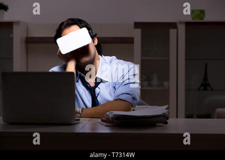 Jeune employé avec des lunettes à la nuit dans le bureau Banque D'Images