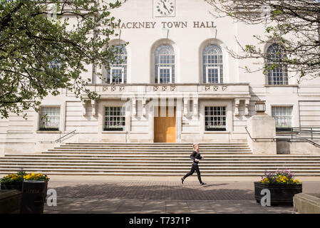 Hackney, Londres, Angleterre, Royaume-Uni - Façade de l'hôtel de ville de Hackney avec woman runner courir devant elle Banque D'Images