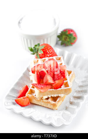 Belgique waffers avec du sucre en poudre et les fraises sur une plaque en céramique sur le tableau blanc. Des wafers. Banque D'Images