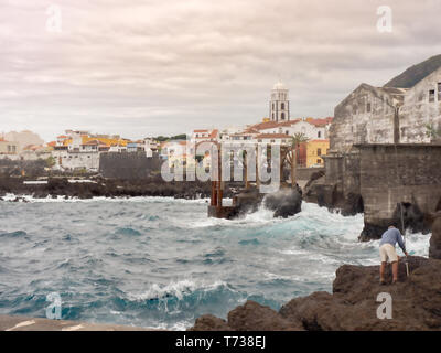 Vue sur la vieille ville Garachico sur Ténérife. L'océan Atlantique est baratté, le ciel est nuageux gris-blanc. La pierre de lave en premier plan et Banque D'Images