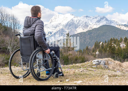 Jeune homme handicapé en fauteuil roulant à l'extérieur dans la nature l'observation de montagne et la nature Banque D'Images