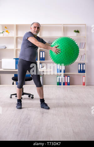 Vieil homme à barbe blanche de faire les exercices de l'employé au bureau Banque D'Images