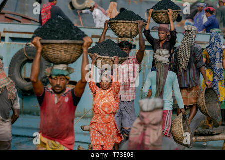 Station d'hommes et femmes de travailleurs sont considérés comme ils décharger le charbon avec des paniers de bambou de ferries au port de la rivière Buriganga à Dhaka, au Bangladesh. Banque D'Images