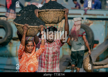 Station d'hommes et femmes de travailleurs sont considérés comme ils décharger le charbon avec des paniers de bambou de ferries au port de la rivière Buriganga à Dhaka, au Bangladesh. Banque D'Images