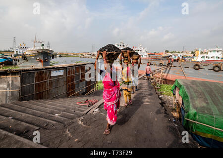 Station d'hommes et femmes de travailleurs sont considérés comme ils décharger le charbon avec des paniers de bambou de ferries au port de la rivière Buriganga à Dhaka, au Bangladesh. Banque D'Images