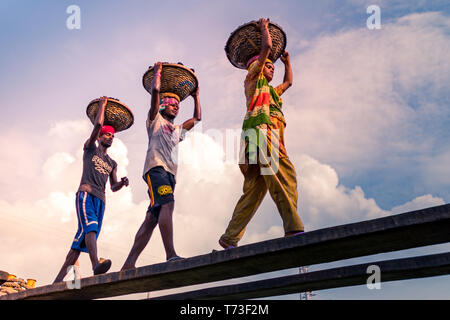 Station d'hommes et femmes de travailleurs sont considérés comme ils décharger le charbon avec des paniers de bambou de ferries au port de la rivière Buriganga à Dhaka, au Bangladesh. Banque D'Images