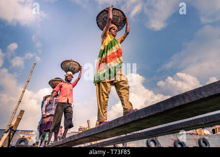 Station d'hommes et femmes de travailleurs sont considérés comme ils décharger le charbon avec des paniers de bambou de ferries au port de la rivière Buriganga à Dhaka, au Bangladesh. Banque D'Images