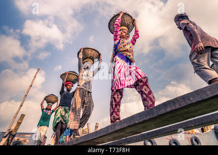 Station d'hommes et femmes de travailleurs sont considérés comme ils décharger le charbon avec des paniers de bambou de ferries au port de la rivière Buriganga à Dhaka, au Bangladesh. Banque D'Images