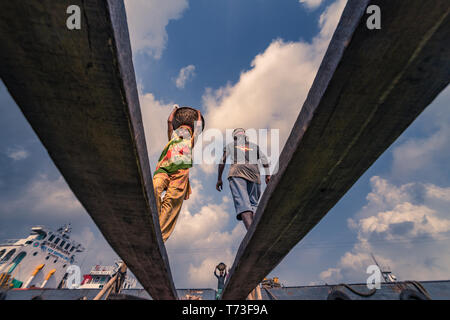 Station d'hommes et femmes de travailleurs sont considérés comme ils décharger le charbon avec des paniers de bambou de ferries au port de la rivière Buriganga à Dhaka, au Bangladesh. Banque D'Images