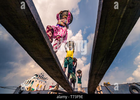 Station d'hommes et femmes de travailleurs sont considérés comme ils décharger le charbon avec des paniers de bambou de ferries au port de la rivière Buriganga à Dhaka, au Bangladesh. Banque D'Images