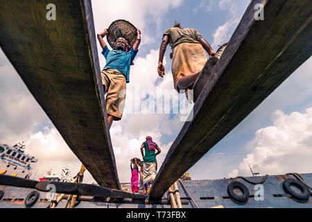 Station d'hommes et femmes de travailleurs sont considérés comme ils décharger le charbon avec des paniers de bambou de ferries au port de la rivière Buriganga à Dhaka, au Bangladesh. Banque D'Images