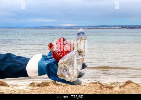 Collecte des déchets en plastique femme sur une plage avec de l'herbe de mer rivage couvert Banque D'Images