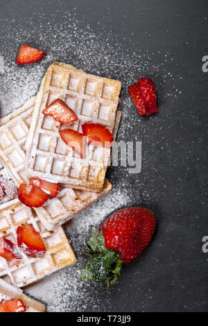 Belgique waffers avec des fraises et du sucre en poudre sur tableau noir l'arrière-plan. Banque D'Images