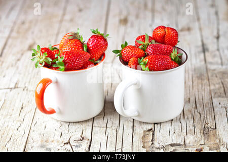 Fraises rouge biologique dans des tasses en céramique blanche sur fond de bois rustique. Une saine alimentation, doux et fruité vitamines concept. Banque D'Images