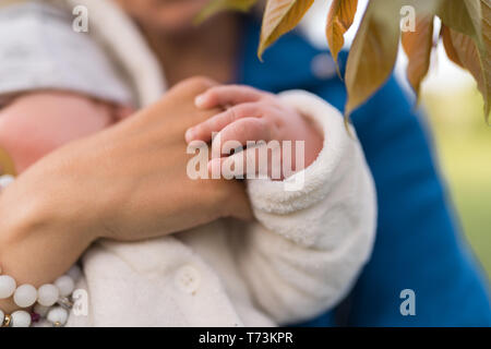 Gros plan sur les mains - jeune mère femme profitant de temps libre avec son enfant de garçon de bébé - enfant blanc caucasien avec la main d'un parent visible - habillé en blanc Banque D'Images