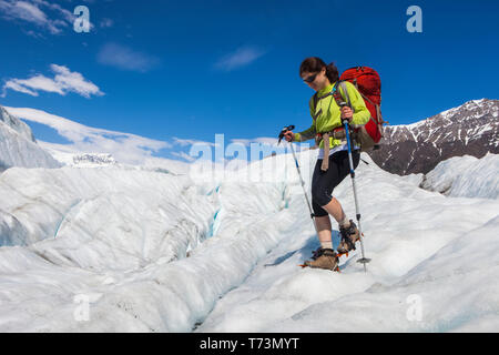 Femme faisant marche arrière sur le glacier racine avec des crampons pendant l'été vers Donoho Peak, Wrangell Mountains, Wrangell-St.Parc national d'Elias,... Banque D'Images