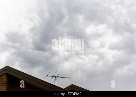 Les nuages d'orage menaçant plus de brassage maison d'habitation avec l'antenne TV. Banque D'Images