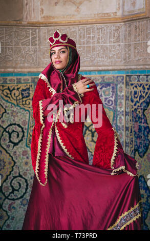 Belle jeune femme iranienne habillés en costume traditionnel rouge dans une mosquée à Kashan Banque D'Images