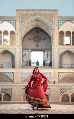 Belle jeune femme iranienne habillés en costume traditionnel rouge dans une mosquée à Kashan Banque D'Images