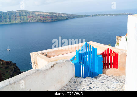Bleu et rouge en bois Portes contre volcan Caldera et la mer Égée à Oia sur l'île de Santorin, Grèce Banque D'Images