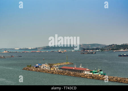 Sihanoukville, Cambodge - Mars 15, 2019 : Sihanoukville Port Autonome sous ciel bleu. Le trafic des navires et les piliers avec des bâtiments aux toits rouges. Green Hills Banque D'Images