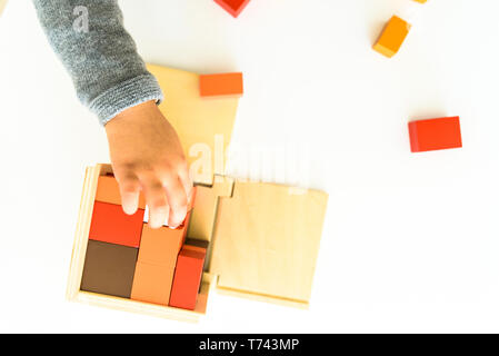 Les mains de l'enfant apprendre à mettre en place les pièces d'un puzzle en bois 3d. Banque D'Images