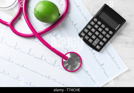 Stéthoscope avec calculatrice et cardiogrammes sur fond de bois. Concept de soins de santé Banque D'Images