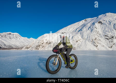 Un homme monté sur son fatbike congelés au lac Portage au milieu de l'hiver dans le centre-sud de l'Alaska ; Alaska, États-Unis d'Amérique Banque D'Images