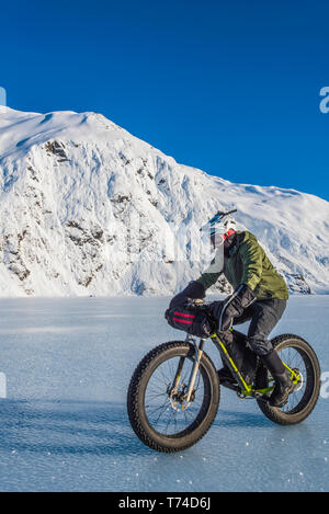 Un homme monté sur son fatbike congelés au lac Portage au milieu de l'hiver dans le centre-sud de l'Alaska ; Alaska, États-Unis d'Amérique Banque D'Images