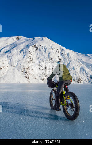 Un homme monté sur son fatbike congelés au lac Portage au milieu de l'hiver dans le centre-sud de l'Alaska ; Alaska, États-Unis d'Amérique Banque D'Images