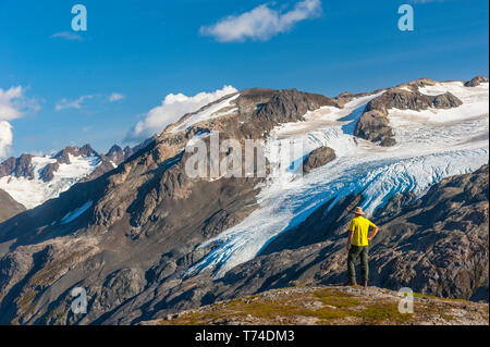 Un homme qui randonnée près de la piste d'Harding Icefield avec les montagnes Kenai et un glacier suspendu sans nom en arrière-plan, Parc national de Kenai Fjords,... Banque D'Images