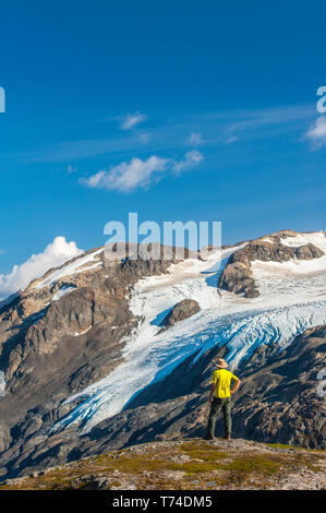 Un homme qui randonnée près de la piste d'Harding Icefield avec les montagnes Kenai et un glacier suspendu sans nom en arrière-plan, Parc national de Kenai Fjords,... Banque D'Images