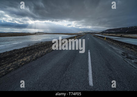 Route qui mène dans le paysage spectaculaire de l'Islande alors que le soleil brille à travers les nuages faire une belle scène ; l'Islande Banque D'Images