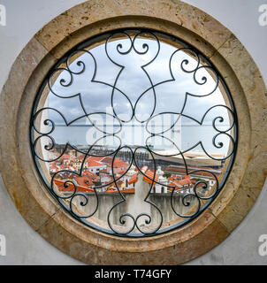 Vue à travers une fenêtre ronde de la rivière Tejo et Alfama du Miradouro de Santa Luzia, Lisbonne, Portugal, Lisboa Région Banque D'Images