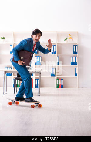 Young handsome businessman avec longboard au bureau Banque D'Images