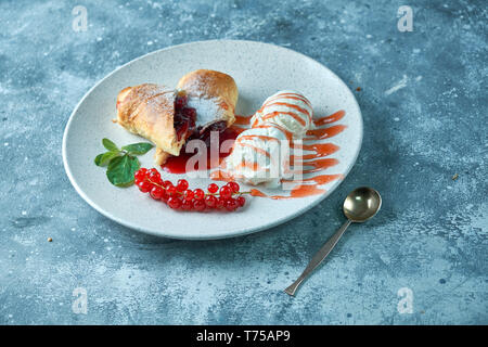 Des tranchées d'un strudel aux fruits rouges frais servi avec des baies de cassis et le sucre en poudre sur une vieille plaque de fond sur un pic avec de la crème glacée Banque D'Images