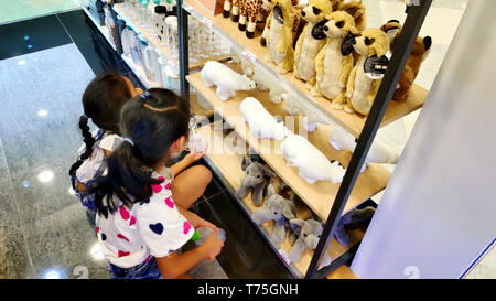 Deux filles asiatiques vietnamiennes cute smiling choisissant brown stuff lions animaux sur étagère pour cadeau d'anniversaire à l'Supermarché Banque D'Images