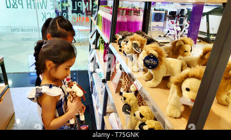 Deux filles asiatiques vietnamiennes cute smiling choisissant brown stuff lions animaux sur étagère pour cadeau d'anniversaire à l'Supermarché Banque D'Images