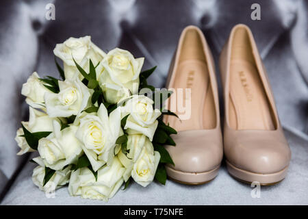 Bouquet de roses blanches à côté de l'épouse hautes chaussures de talon Banque D'Images