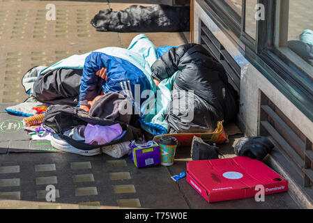 Deux sans-abri et leur chien à l'extérieur d'un magasin sur place du marché en centre-ville de Cambridge, Cambridgeshire, Angleterre, Royaume-Uni. Banque D'Images