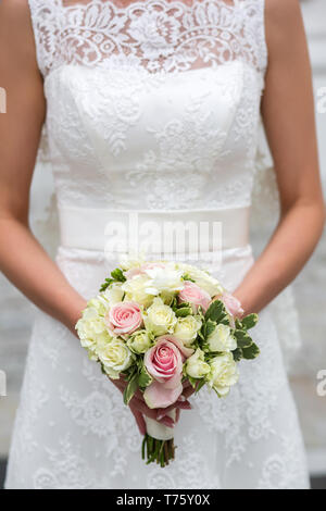 Méconnaissable bride holding a bouquet de mariage raffiné de roses roses et blanches Banque D'Images