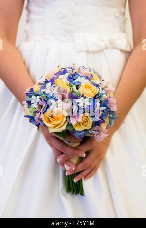 Charmant mariage bouquet de roses jaunes et bleu Hortensia à orchidées dans les mains d'une femme méconnaissable Banque D'Images