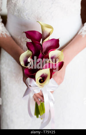 Méconnaissable bride holding a bouquet de mariage raffinés de blanc et crimson callas Banque D'Images