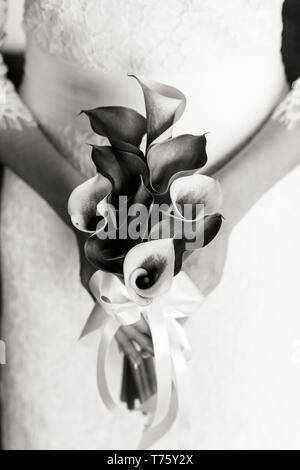 Méconnaissable bride holding a bouquet de mariage raffiné de Callas, photo en noir et blanc Banque D'Images