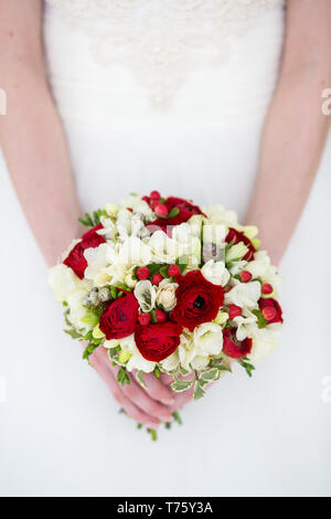 Méconnaissable bride holding a bouquet de mariage raffiné de roses rouges et blanc freesia Banque D'Images