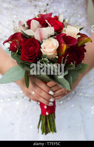 Charmant bouquet de mariage de rose et roses rouges dans les mains d'une femme méconnaissable Banque D'Images