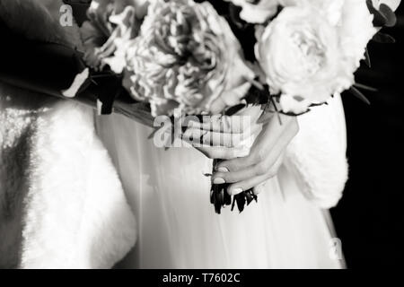 Bouquet de mariage exquis dans les mains d'une femme méconnaissable, tourné en noir et blanc Banque D'Images