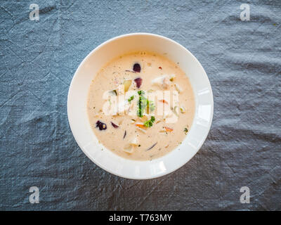 Soupe de Poisson norvégienne avec la morue et le saumon dans une assiette blanche, haut Vue de dessus. Banque D'Images